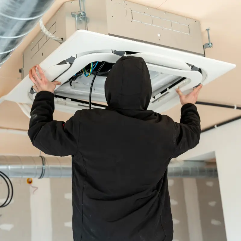 Professional technician installing a cassette split air conditioner unit in a false ceiling.